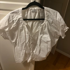 Vit blus från Wera - Säljer en vit blus från Wera med korta ärmar och v-ringad hals. Blusen har en luftig passform och är perfekt för varmare dagar. Den är tillverkad i ett lätt och bekvämt material.