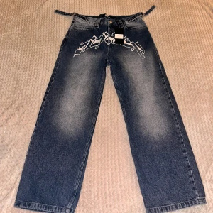 Vicinity Baggy jeans - Snygga mörkblå jeans från Vicinity med coolt vitt tryck framtill. Byxorna har en loose passform och är tillverkade i 100% bomull. Perfekta för en avslappnad stil med en unik touch. Formen är i baggy/loose fit.