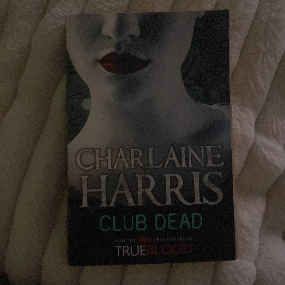 Boken 'Club Dead' av Charlaine Harris är en del av serien som inspirerade TV-serien True Blood. Omslaget har en mystisk design med en blek ansiktsbild och mörka läppar, vilket ger en gotisk känsla. Perfekt för fans av urban fantasy och vampyrberättelser.. Böcker.