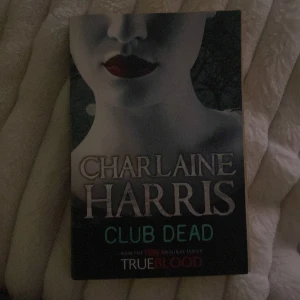 Club Dead - Boken 'Club Dead' av Charlaine Harris är en del av serien som inspirerade TV-serien True Blood. Omslaget har en mystisk design med en blek ansiktsbild och mörka läppar, vilket ger en gotisk känsla. Perfekt för fans av urban fantasy och vampyrberättelser.