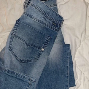 Blå jeans från Diesel - Snygga blå jeans från Diesel med klassisk femficksdesign och knappgylf. Perfekta för en avslappnad stil med en lätt tvättad look.