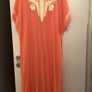 En jätte fin marockanska natt klänning den går bra och att vara ute inne när gäster kommer bra skick älskar den men tyvärr fick den ej plats på mej Stolek XL men får ocå plats i L,S,M ❤️ - Snygg orange kaftan med v-ringning och vackra broderade detaljer i vitt. Perfekt för en avslappnad dag eller en somrig kväll. Lätt och luftig design med korta ärmar.