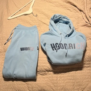 Ljusblå hoodie från Hoodrich - Jag säljer denna snygga tracksuit då den är för stor. Den är väldigt snygg att använda och skön på vintern men funkar lika bra på sommaren. Den är använd 3 gånger då jag tycker den är för stor hör av er om pris. Byxorna är L och tröjan är M, byxorna passar jättebra om du är cirka 183 eller längre. Nästan helt ny och kostar 800 för tröjan på JD sports 