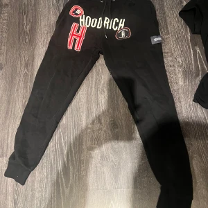 Svarta mjukisbyxor från Hoodrich - Snygga svarta mjukisbyxor från Hoodrich med tryck i vitt och rött. Byxorna har en bekväm passform med resår i midjan och muddar vid bensluten. Går inte att köpa längre !! 