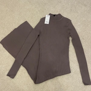 Brun ribbad/stickad klänning från New Look - Helt ny och oanvänd med prislappen kvar. Snygg brun ribbad klänning med lång ärm och slits. Perfekt för en stilren look. Klänningen är figurnära och har en elegant längd. Skriv för mer information 🩷