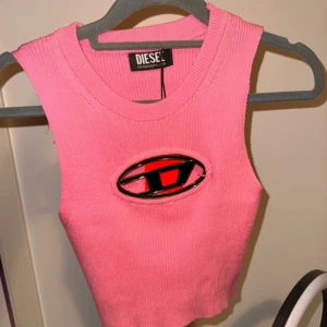 Rosa ribbad linnetopp från Diesel - Säljer en snygg rosa ribbad linnetopp från Diesel med ett coolt emblem framtill. 