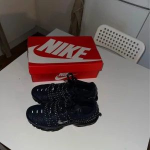 Svarta Nike tn skor  - Snygga svarta Nike sneakers med vit logga och snörning. Skorna har en modern design med en bekväm sula och stickade detaljer. Perfekta för både träning och vardag.och ha ute i snön