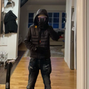 Parajuamper jacka  - Snygg svart dunjacka med huva och dragkedja. Perfekt för kyliga dagar. Jackan har en stilren design med diskreta detaljer och en bekväm passform.