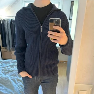 Stickad fullzip-tröja i toppskick! - Snygg stickad fullzip-tröja i toppskick! Modellen är 187 cm lång och väger 83 kg, vilket gör det enkelt att jämföra passformen. Tröjan är i 100 % bomull, i nyskick och knappt använd. Vid intresse är det bara att höra av dig – DLVClothing_sth ser fram emot att ge dig en snabb och smidig affär! Mvh, DLVClothing_sth