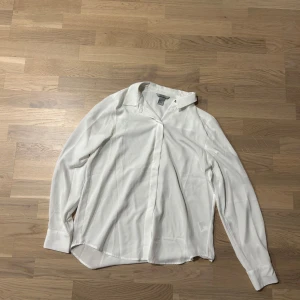 Vit långärmad skjorta - Snygg och klassisk vit skjorta med långa ärmar och knappar framtill. Perfekt för en stilren look.