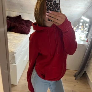 Röd hoodie - Säljer en mysig röd hoodie med justerbar huva och ficka framtill. Perfekt för kyliga dagar och avslappnade stunder. Passar bra till jeans eller leggings.