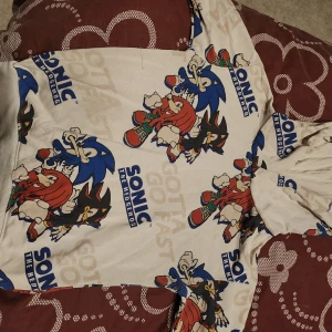 Vit hoodie med Sonic-motiv - Cool vit hoodie med färgglatt Sonic the Hedgehog-motiv. Perfekt för fans av den ikoniska spelkaraktären. Hoodien har långa ärmar och en bekväm passform.