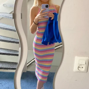 Randig klänning från H&M - Säljer denna färgglada sköna klänning från H&M i storlek XXS. Klänningen har ett ribbat material med ränder i rosa, blått, gult och lila. Den är ärmlös och har en stretchig passform som sträcker sig till nedanför knäet. Klänningen passar även storlek S eftersom den är så stretchig. Klänningen är använd 1 gång och har inga tecknen på användning.