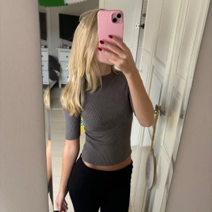 Ribbstickad tröja - Säljer en grå ribbad topp med trekvarts ärmar. Toppen har en tight passform och är perfekt för en trendig look.