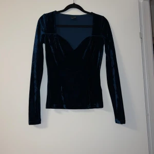 Mörkblå sammetstopp från Gina Tricot - Snygg mörkblå sammetstopp från Gina Tricot med långärmad design och en elegant v-ringning. Perfekt för en stilren look.