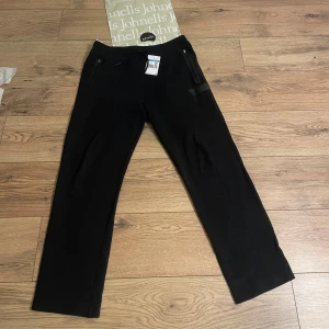 Mjukisbyxor från Boss - Snygga mjukisbyxor från Boss med en stilren design. Byxorna har en dragkedja och en diskret logga på. Mjukisbyxorna är straight. Helt ny oanvända köpt för 1799kr! Dom är inte helt svarta blandad med marinblå färg!