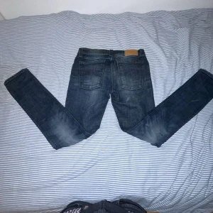 Mörkblå jeans från Nudie Jeans - Säljer ett par mörkblå jeans från Nudie Jeans i storlek 28/30. De har en slim passform och klassisk femficksdesign. Perfekta för en stilren look. Modell skinny Linn! Priset kan självklart diskuteras!