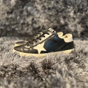 Golden Goose sneakers  - Snygga svarta sneakers med en vit stjärndetalj på sidan. Perfekta för en stilren look. Säljs i befintligt skick Storlek 43. 
