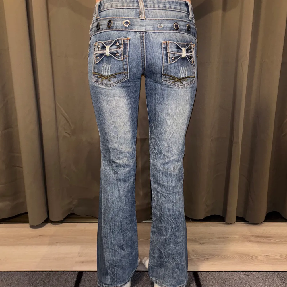 Snygga blå jeans från LJJ Jeans med unika rosett-detaljer på bakfickorna. Jeansen har en klassisk femficksdesign och dekorativa knappar vid midjan. Byxorna är utsydda till bootcut därmed en extra söm, innerbenslängden 78 cm och tvärs lver midjan 37 cm ❤️ PRISET ÄR DISKUTERBART!!! ❤️. Farkut & Housut.