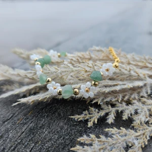~Handgjort grönt och vitt armband~ - Ett fint armband med gröna stenar och vita pärlor samt guldfärgade detaljer. Perfekt för att ge en färgklick till din outfit. Armbandet har en design med små vita blommor mellan de gröna stenarna. Armbandet har smyckeslås och kedja i guld.