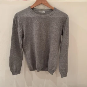 Grå J Lindeberg Kashmir tröja - Grå JLindeberg stickad tröja i kashmir och ull blandning. 70% kashmir, 30% ull i bra skick. Är en liten dam large men är unisex. Passar om du är runt 165-175 cm lång.