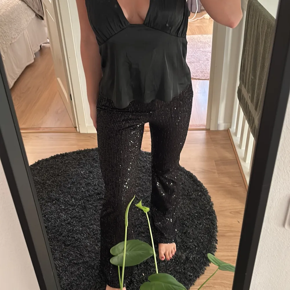 Snygga svarta byxor med paljetter som ger en glittrig look. Perfekta för en festlig kväll. Byxorna har en tight passform och är midwaist. De är både bekväma och stiliga. SE DEFEKTER PÅ SISTA BILDERNA, har varken orken eller kundskapen för att sy men går bra att lämna in dom eller testa själv för billigt pris!. Farkut & Housut.