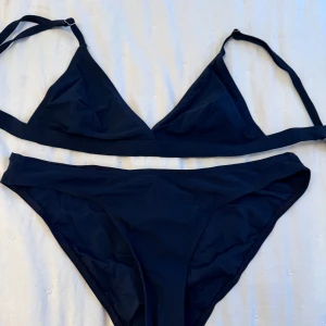 Svart bikini från Filippa K - Snygg svart bikini från Filippa K med enkel design. Toppen har justerbara axelband och trekantsformade kupor. Överdel i storlek Xs och underdel i storlek S.