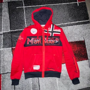 Röd huvtröja från Geographical Norway - Snygg röd huvtröja från Geographical Norway med dragkedja. Varm o mysigt material samt riktigt go passform. Hoodien är i super bra skick, inga slitningar  eller något annat.