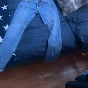 Blå jeans från Gant - Säljer ett par klassiska blå jeans från Gant. De har en normal passform och är perfekta för en avslappnad stil. Jeansen har en knappgylf och är tillverkade i ett slitstarkt denimtyg.