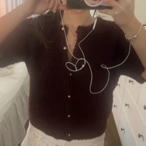 Vinröd kofta med knappar - Säljer en vinröd kofta med korta ärmar och knappar framtill. Perfekt för en stilren look.