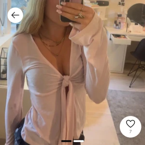 Rosa långärmad topp med knyt - Säljer en söt rosa långärmad topp med knyt framtill. Toppen har en djup v-ringning och är perfekt för en trendig look. Passar bra till jeans eller kjol.