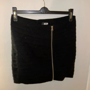 Svart kjol från Bik Bok - Säljer en snygg svart kjol från Bik Bok i storlek S. Kjolen har en cool dragkedja framtill och är perfekt för både vardag och fest. Den är i bra skick och har en stilren design som passar till allt. Perfekt för höst och vinter!
