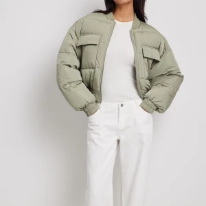 Olivgrön pufferjacka - Säljer en supercool VIT JACKA  pufferjacka som är perfekt för kyliga dagar. Jackan har en dragkedja framtill och stora fickor på bröstet. Den är långärmad och har en oversized passform som ger en avslappnad look. Perfekt för höst och vinter!