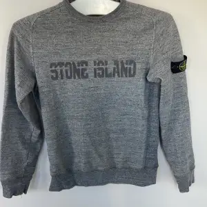 En grå Stone Island tröja i bra skick. Storlek: 12-14 år  Äkta  Säljer den för att den är för liten för mig Bra skick