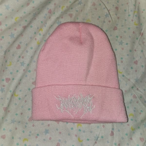 Rosa mössa - En rosa mössa med ett broderat mönster pål framsidan. Den är helt ny.