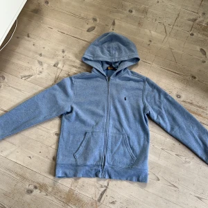 Polo Ralph lauren-hoodie - Har haft den i ungefär ett halv år. Säljer på grund av att den är för liten för mig. Skick 9/10. Riktigt fin polo hoodie! Storlek L(14-15). Pris kan såklart diskuteras, det är bara att skriva!