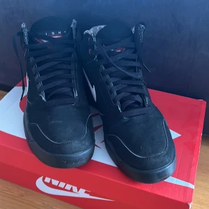 Svarta Nike Air sneakers - Säljer ett par svarta Nike Air sneakers i storlek 45. Skorna har en klassisk design med vit swoosh och röd Nike Air-logga på hälen. De är i bra skick och kommer med originalkartong. Perfekta för både vardag och träning! PSST! (Pris kan diskuteras!)