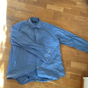 Stenströms skjorta - Blå rutig stilren skjorta från stenströms i storlek 41 vilket motsvarar M/L. Den är i bra skick men har en liten fläck vid vänster sida magen (se bild 3) som jag inte har testat att ta bort. Hör av er vid frågor. Priset kan diskuteras 