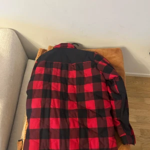 Röd och svart rutig jacka från Peak Performance - Säljer en snygg röd och svart rutig jacka från Peak Performance. Jackan har långa ärmar och en cool design med ett diskret märke på ärmen. Perfekt för en stilren look.