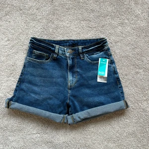 Mörkblå jeansshorts - Säljer ett par jeansshorts i storlek S från Ica Maxi. Shortsen är oanvända (endast testade) och går att vika upp och ner beroende på hur korta respektive långa man vill ha dem. Köparen står för frakten🤍
