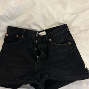 Svarta jeansshorts från Zara - Snygga svarta jeansshorts från Zara mid- waist och knappgylf.