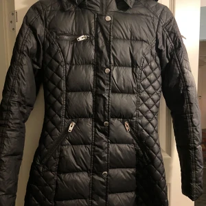 Svart jacka från Rockandblue - Svart jacka från Rockandblue med dragkedja och knappar. Jackan har en huva och flera praktiska fickor med dragkedjor. Perfekt för kyligare dagar.😇