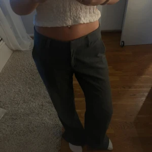 Grå kostymbyxor - Snygga grå kostymbyxor med en klassisk straight passform. Perfekta för en stilren look. Byxorna har en låg midja och är tillverkade i ett bekvämt material.