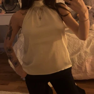 Vit ärmlös topp - Snygg vit ärmlös topp med hög hals. Perfekt för en stilren look. Passar bra till både jeans och kjol.