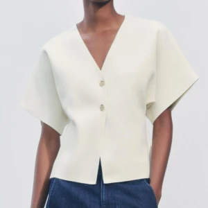 Vit v-ringad blus med knappar - Superfin slät stickad topp från Zara med guld knappar. Använd 2 gånger så i fint skick. Storlek M men passar S lika bra 🥰