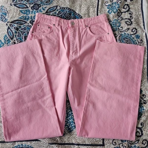 Rose wide and loose jeans - Snygga rosa jeansbyxor med hög midja och vida ben. Perfekta för att ge en färgklick till din outfit. Klassisk femficksdesign med knapp och dragkedja framtill.Aldrig använd!  Hög midja!  Jeans utan stretch! Jeans med mer avslappnad och vid passform 100 % bomull