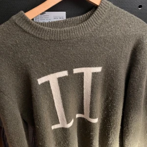 Olivgrön tröja från Les Deux - Säljer en stilren olivgrön tröja från Les Deux med vita bokstäver på framsidan. Tröjan har en rund halsringning och är perfekt för en avslappnad look. Passar bra till både jeans och chinos. Finns fler bilder vid förfrågan!