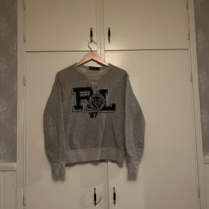 Grå sweatshirt från Polo Ralph Lauren - Säljer en grå sweatshirt från Polo Ralph Lauren. Passar perfekt till dig som bär storlek S. 🔥😎Riktigt fin tröja och har inte hunnit använda den så mycket då jag växt.