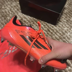 Adidas F50 fotbollsskor - Köpte fel storlek och kunde inte lämna tillbaka , helt oanvända och knappt rörda från paketet förutom när jag ska ta bilden. Snygga och sportiga Adidas F50 fotbollsskor i en iögonfallande röd färg med svarta detaljer. Skorna har snörning och är designade för optimal prestanda på planen. Perfekta för fotbollsspelare som vill ha både stil och funktion.  