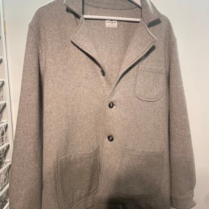 Grå kavaj från John Henric - Säljer en stilren grå kavaj från John Henric. Kavajen har en klassisk design med knappar framtill och tre fickor. Perfekt för en elegant look.